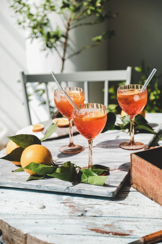 Aperol Spritz cocktail in glasses with fresh orange on table