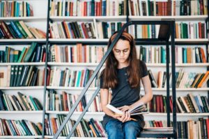 Children's education. Girl reading book at library.